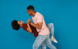 © Drobot Dean - Excited positive afro couple dancing isolated over blue background