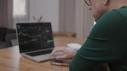 Poster - Back view of man in eye glasses analysing stock market charts on laptop at home. Bitcoin and crypto currency investment concept.