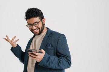 Wall Mural - Cheerful indian man using smartphone isolated over white background