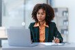 © M+Isolation+Photo - Online consult with laptop, video conference, Young pretty african american business woman bookkeepers working with balance sheet yearly reports to calculate tax and online consult in modern office.