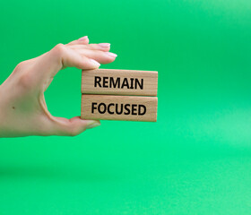 Remain focused symbol. Concept words Remain focused on wooden blocks. Businessman hand. Beautiful green background. Business and Remain focused concept. Copy space.