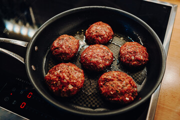 Wall Mural - Meatballs fry in fat in a frying pan on an induction cooker in a private kitchen