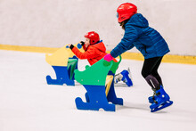 Children Using Helpers For Skating On Ice Rink