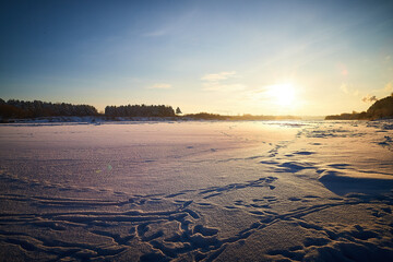 Wall Mural - Photo of a sunset at winter snowy field, peaceful stunning landscape, amazing seasonal nature, cold weather in the park, beautiful sunny snow field, wintertime scene, icy lands