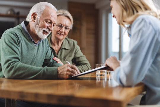 happy senior couple signing a document with their financial advisor at home