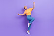 © deagreez - Full size photo of optimistic gorgeous nice girl dressed sneakers denim pants dancing having fun isolated on purple color background