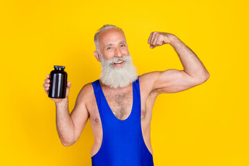 Canvas Print - Portrait of positive powerful grandfather show empty space supplement bottle flex biceps isolated on yellow color background