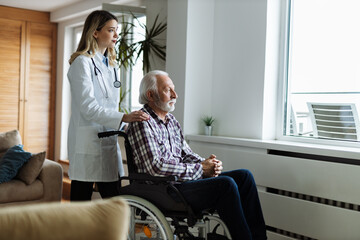 Wall Mural - Young female nurse caring for her senior patient in a wheelchair at home