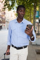 Wall Mural - African american tourist on the street writes message on the mobile phone screen