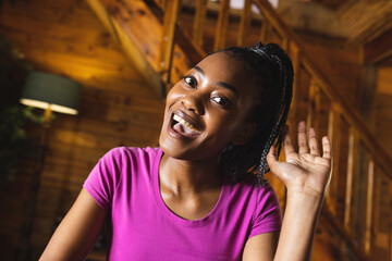 Wall Mural - Portrait of happy african american woman spending time in log cabin and having video call