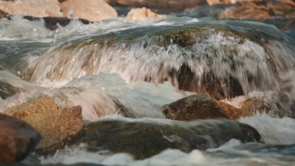 Wall Mural - River flowing over rocks cascade on sunny day, closeup detail