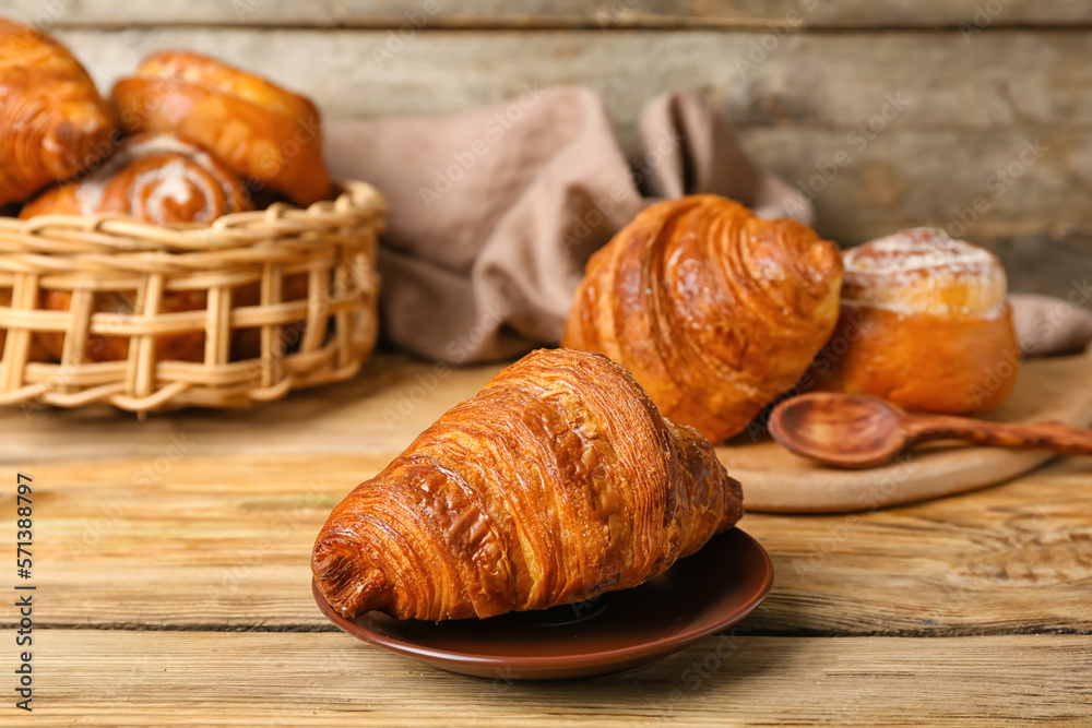 Plate with delicious croissant on wooden table