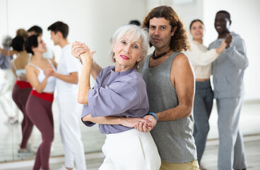 Wall Mural - Caucasian man and mature woman rehearsing latin paired dance moves