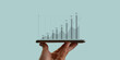 © Tarokmew - Hand holding smart phone and financial performance showing the financial growth and development of the business increases year by year. Technology makes it easy to access financial information.