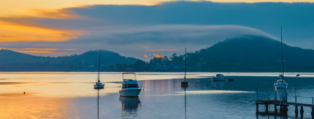 Aerial sunrise waterscape panorama with boats and fog