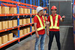 © feeling lucky - Group of warehouse workers men with hardhats and reflective jackets carrying a large box for delivery to production stock and inventory in retail warehouse logistics, distribution center