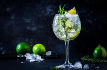 Gin Tonic Cocktail With Dry Gin, Rosemary, Tonic, Lime And Ice Cubes In Wine Glass. Black Bar Counter Background, Bar Tools, Copy Space