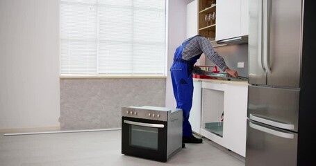 Wall Mural - Young Repairman Installing Induction Cooker