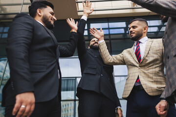 Business people outdoor meeting. Team join forces and celebrate success by throwing their hands up. Stacking hands