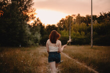 Back View Of Young Woman Walking Away On Country Road During Summer