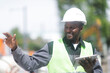 © Cavan Images - worker young male with helmet and tablet outside looking