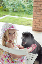Girl Sitting In The Yard With A Big Black Dog