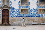 Fototapeta Zachód słońca - Tourist walking, azulejos tiles over Chapel Of Souls, Porto, Portugal