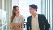 © M Stocker - Two asian businesspeople walking and talking about their business in modern corporate office