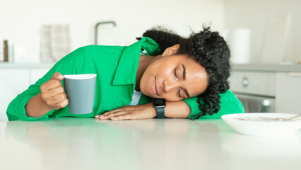 Wall Mural - Tired Black Woman Sleeping Holding Coffee Having Breakfast In Kitchen