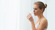 © Acronym - Young woman in white underwear is standing in front of the window and looking into it. Girl at home in the living room.