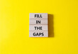 Fill in the gaps symbol. Concept words fill in the gaps on wooden blocks. Beautiful yellow background. Business and fill in the gaps concept. Copy space.