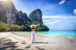 © moofushi - A happy tourist woman in a white dress and stands on the beautiful beach of Railay at the Krabi area, Thailand, without people