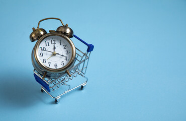 Wall Mural - Alarm clock, shopping cart on the blue background.