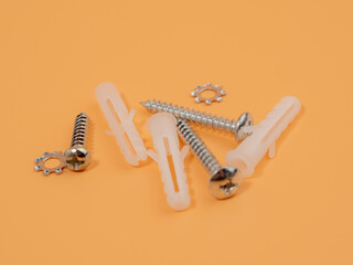 Screws and plastic dowels on an orange background. Bolts and dowels.