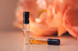 Two perfume samples with aroma water against peonies in soft focus. Face serum, essential oil, fruit peeling on floral background. Natural beauty product presentation. Front view. Mockup