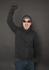 Wall Mural - Screaming Man in the black hoody with hood wearing sunglasses with fist up