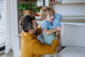 Father changing t-shirt to his little son.