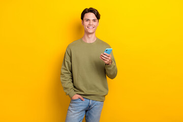 Canvas Print - Portrait of positive nice man hold use telephone toothy smile write typing isolated on yellow color background