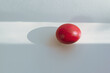 single red painted easter egg on white table with shadow