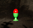 red painted easter egg in cup front of black background