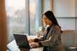 © Drazen - Asian female CEO working on laptop at corporate office.