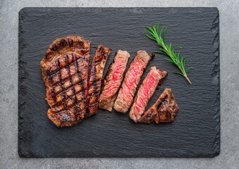 Sticker - Grilled  delicious ribeye steak slices and rosemary twig on black slate serving plate. Flat lay.