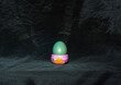 single green easter egg in cup front of black background