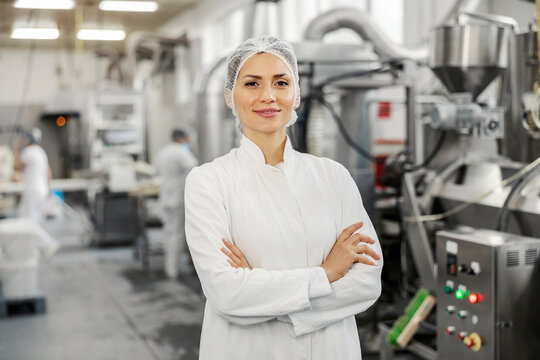 portrait of a successful food factory manager in sterile uniform with arms crossed smiling at the ca
