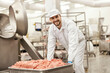 © Dusan Petkovic - A happy meat factory worker is pushing a container full of raw ground meat in facility.