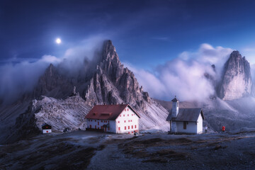 Wall Mural - mountains in fog with beautiful house and church at night in summer. landscape with high rocks, blue