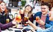 Trendy friends toasting drinks at fancy restaurant out side - Life style concept with young people having fun together on happy hour at sidewalk cocktail bar - Vivid filter with focus on middle woman