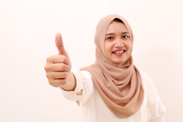 Close up photo of thumbs up from young asian muslim woman. Selective focus. Isolated on white