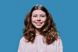 Fototapeta Młodzieżowe - Portrait of smiling child schoolgirl on blue studio background