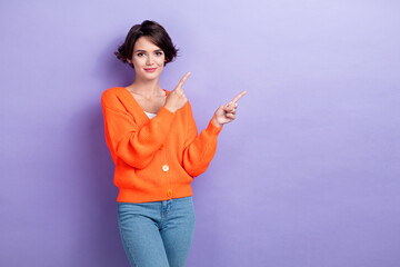 Photo of pretty shiny lady dressed orange cardigan smiling pointing two fingers empty space isolated purple color background